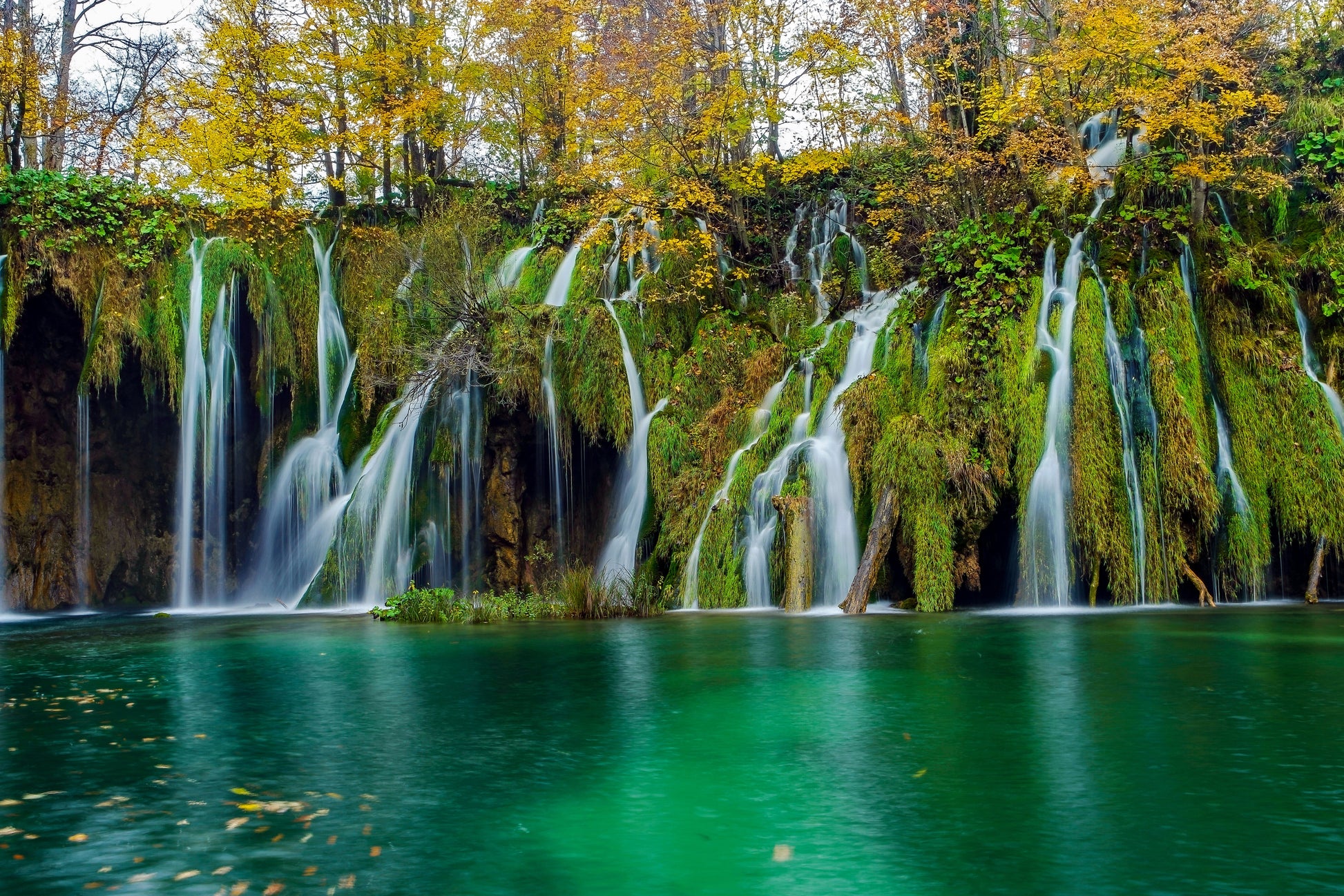 Tablou canvas cu cascade peste mușchi verde și lac turcoaz